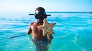 Black boy in ocean with starfish
