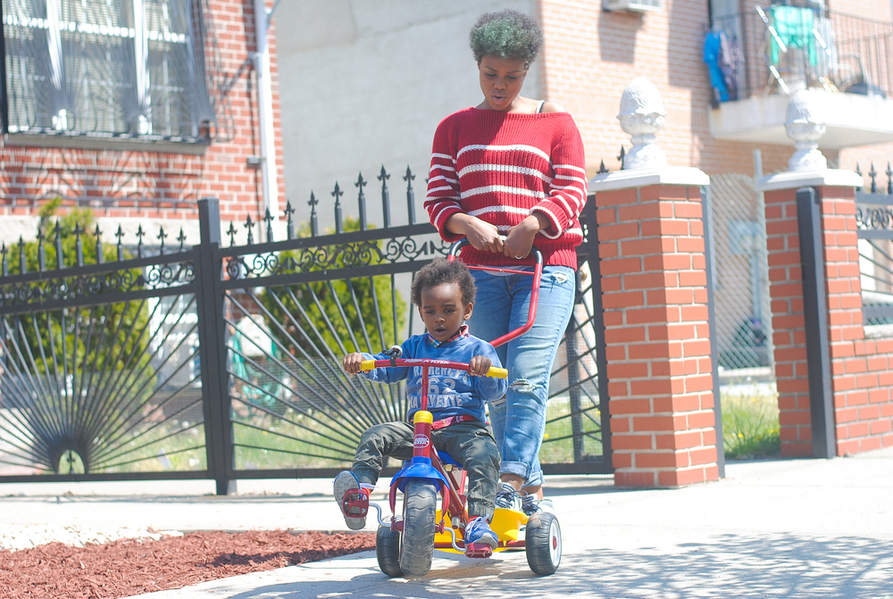 Khalilah Beavers pushing her son on his tricycle
