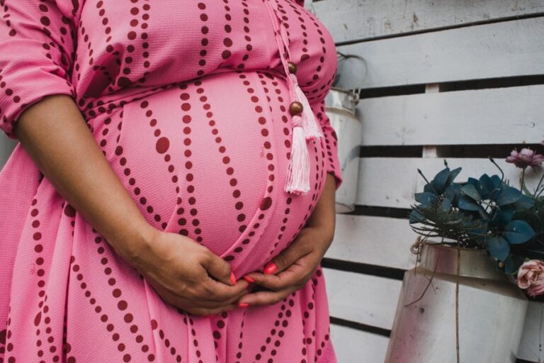 pregnant woman in pink dress holding belly