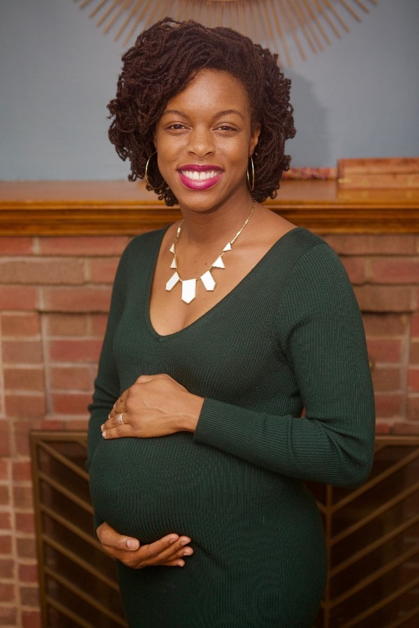 pregnant Black woman in green dress holding belly