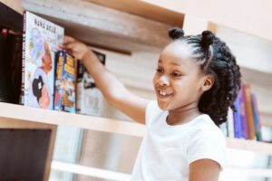 Black girl pulling book from shelf