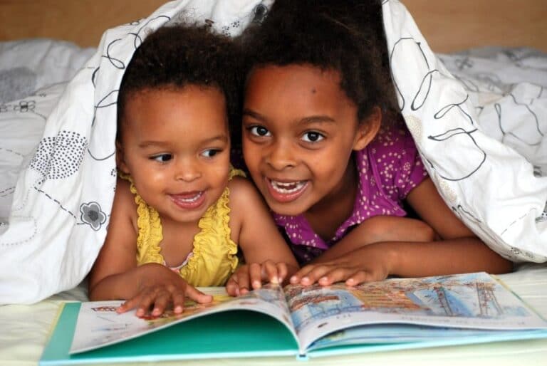 cute kids reading under a blanket